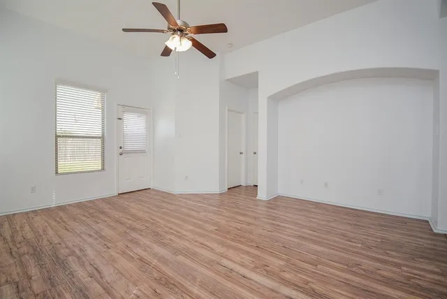 a view of empty room with wooden floor and fan