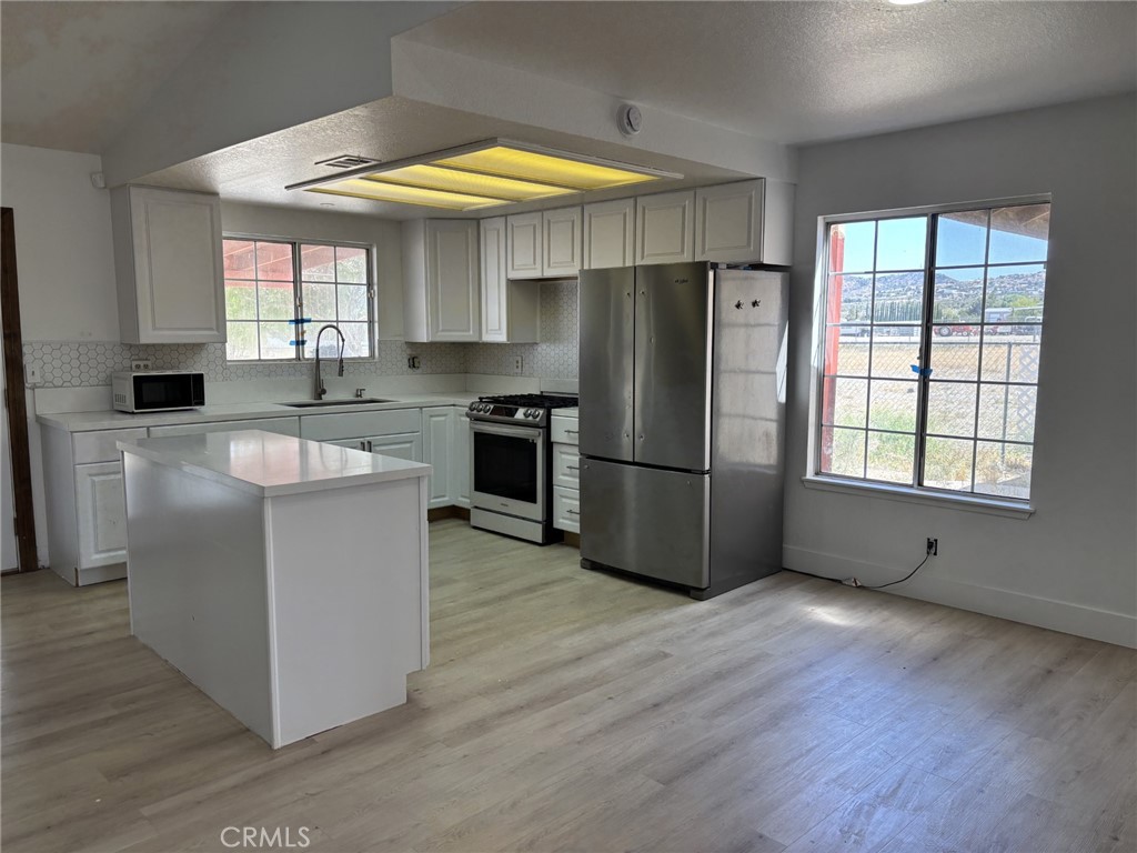 9591 Colfax Road Phelan, CA 92371 - Photo 13 of 24 a kitchen with wooden cabinets stainless steel appliances and a window