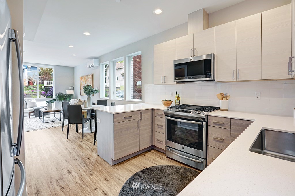 515 Northwest 70th Street Seattle, WA 98117 - Photo 13 of 32 a kitchen with stainless steel appliances granite countertop a stove top oven a sink a dining table and chairs with wooden floor
