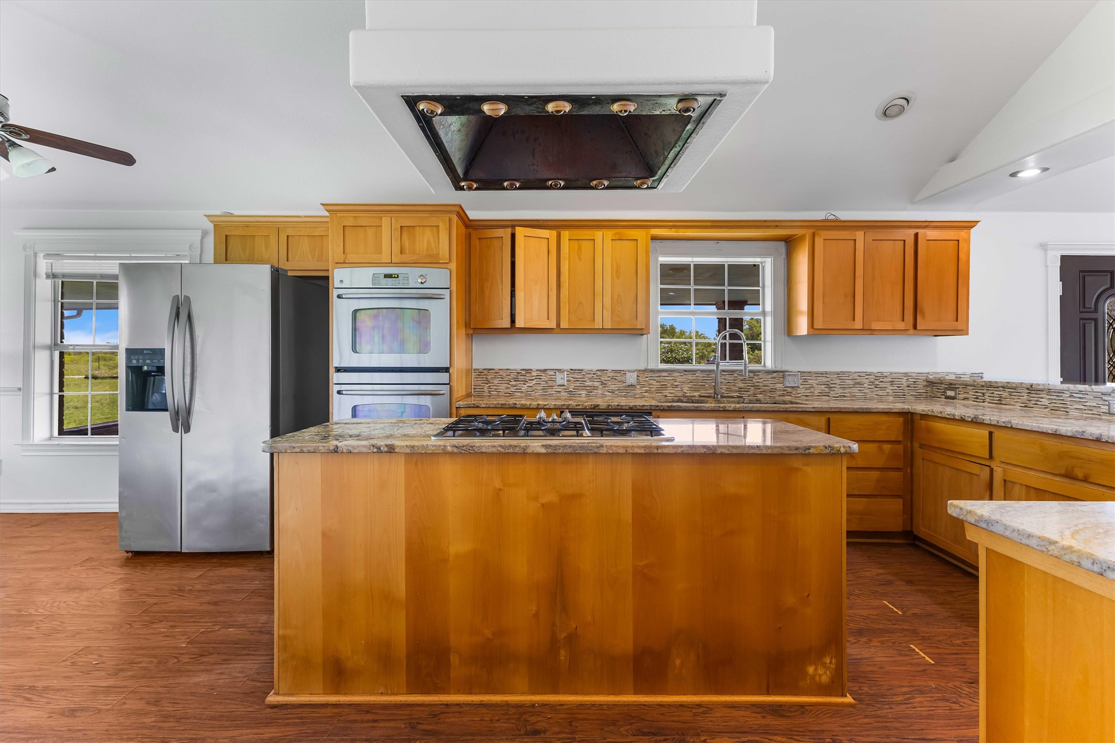 12212 Ballerstedt Road Elgin, TX 78621 - Photo 12 of 39 Kitchen featuring ventilation hood, a center island, stainless steel appliances, light stone countertops, and a ceiling fan