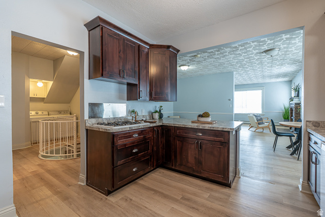 33 North 200 East Logan, UT 84321 - Photo 14 of 54 Kitchen with dark brown cabinetry, light countertops, light wood finished floors, a peninsula, and washer and clothes dryer