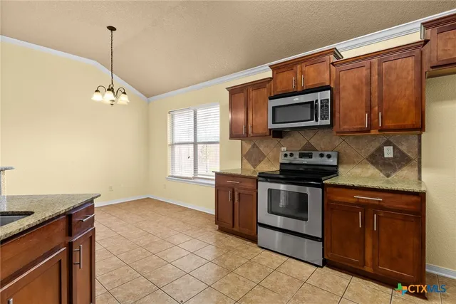 a kitchen with stainless steel appliances granite countertop a stove a sink and a microwave