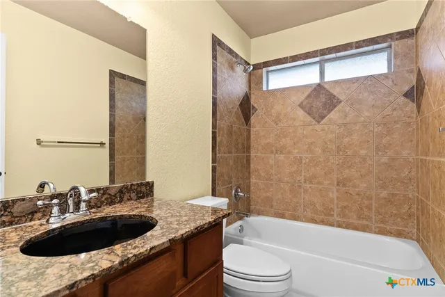 a bathroom with a granite countertop sink a toilet a bathtub and shower