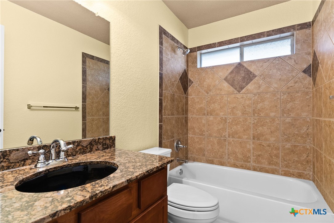 5705 Bald Ridge Court Killeen, TX 76542 - Photo 21 of 28 a bathroom with a granite countertop sink a toilet a bathtub and shower