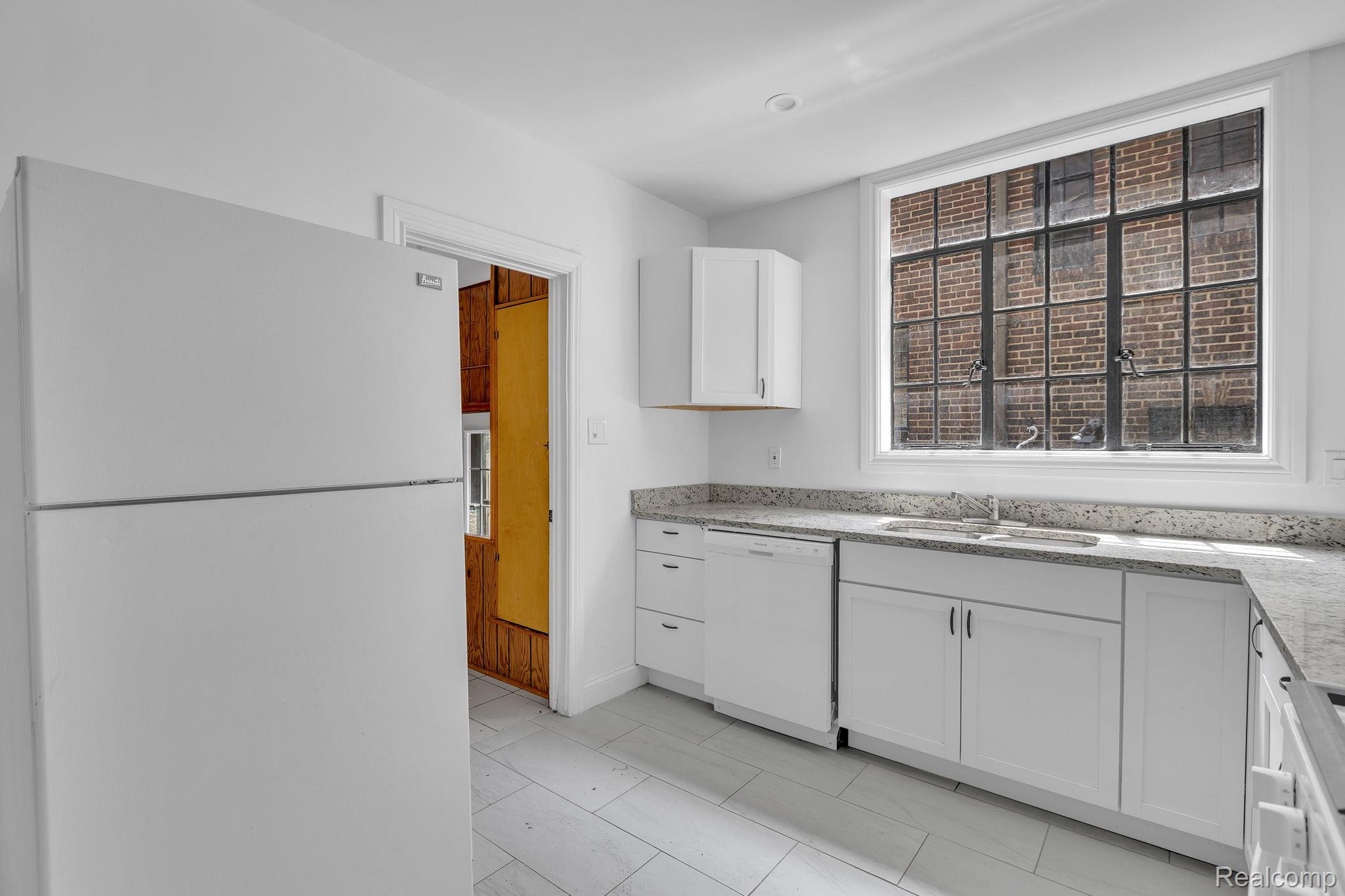 19510 Stratford Road Detroit, MI 48221 - Photo 21 of 45 Bright kitchen featuring white cabinetry, granite-style countertops, an undermount sink, and tiled flooring