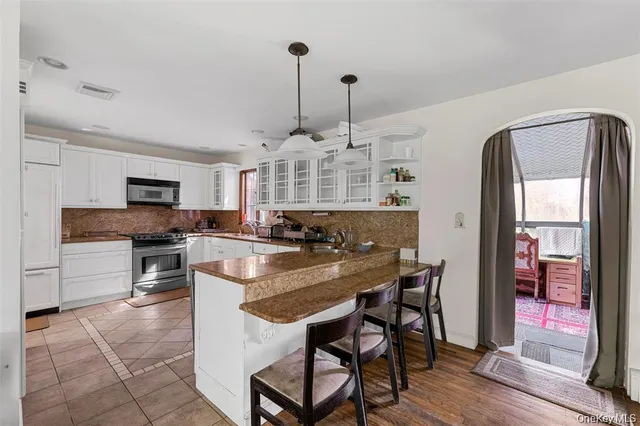 a kitchen with stainless steel appliances granite countertop a stove top oven a sink dishwasher a dining table and chairs with wooden floor