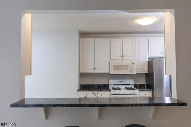 a kitchen with kitchen island granite countertop a sink stove and cabinets