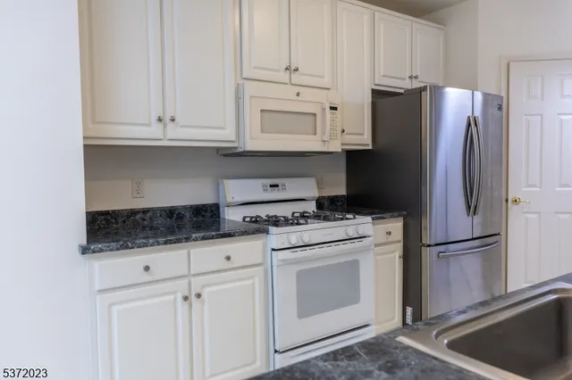 a kitchen with granite countertop white cabinets and stainless steel appliances