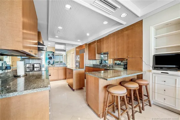 a kitchen with stainless steel appliances kitchen island granite countertop a table chairs sink and cabinets