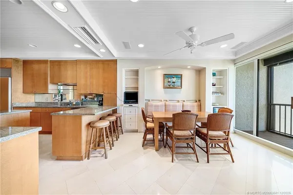 a dining hall with stainless steel appliances kitchen island granite countertop a table and chairs