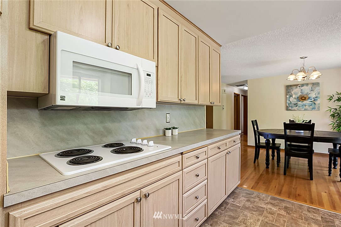 2608 Northeast 18th Street Renton, WA 98056 - Photo 10 of 20 a kitchen with stainless steel appliances granite countertop a white stove top oven a sink dishwasher and white cabinets with wooden floor