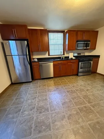 a large kitchen with granite countertop a stove a microwave and a sink
