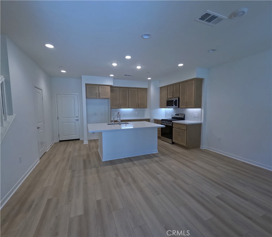 32336 Brunello Way Temecula, CA 92591 - Photo 4 of 25 a view of kitchen with kitchen island wooden floors stainless steel appliances a sink