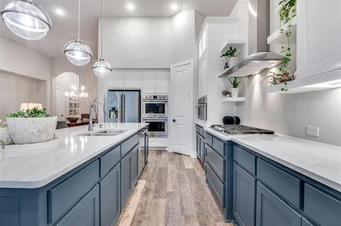 a kitchen with kitchen island granite countertop a sink a counter top space stove and cabinets