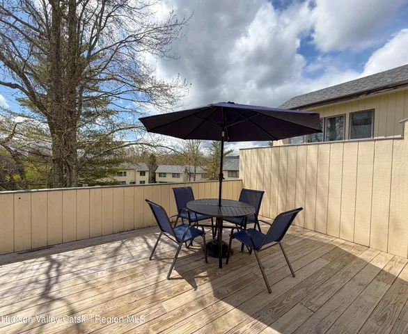 a view of a roof deck with table and chairs under an umbrella with wooden floor