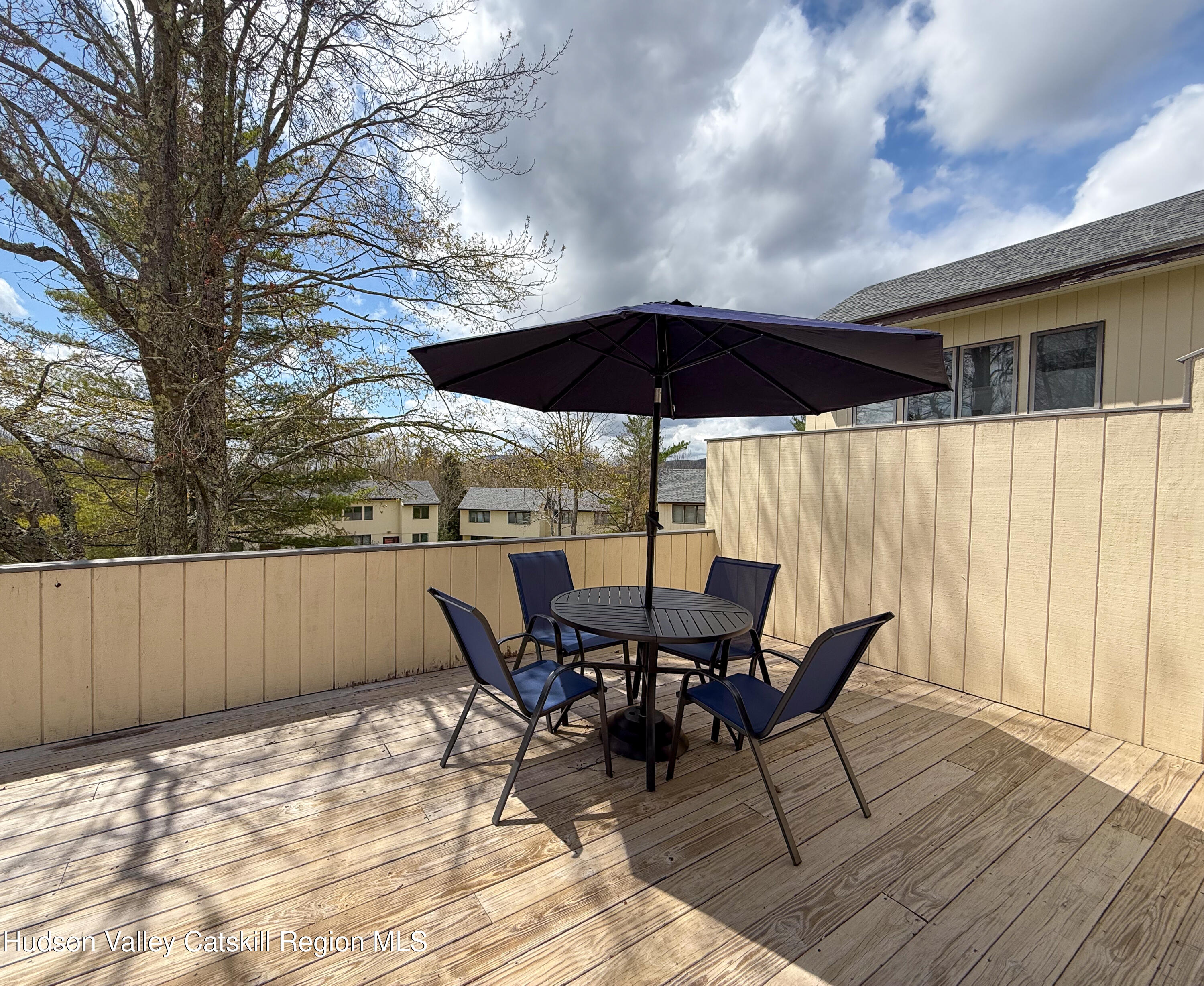 130 Pines Drive, Unit 59 Roxbury, NY 12421 - Photo 31 of 34 a view of a roof deck with table and chairs under an umbrella with wooden floor