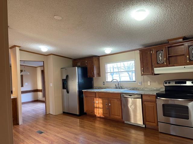 2740 Rutrough Road Southeast Roanoke, VA 24014 - Photo 16 of 27 a kitchen with stainless steel appliances granite countertop a stove a sink and a refrigerator with wooden floors
