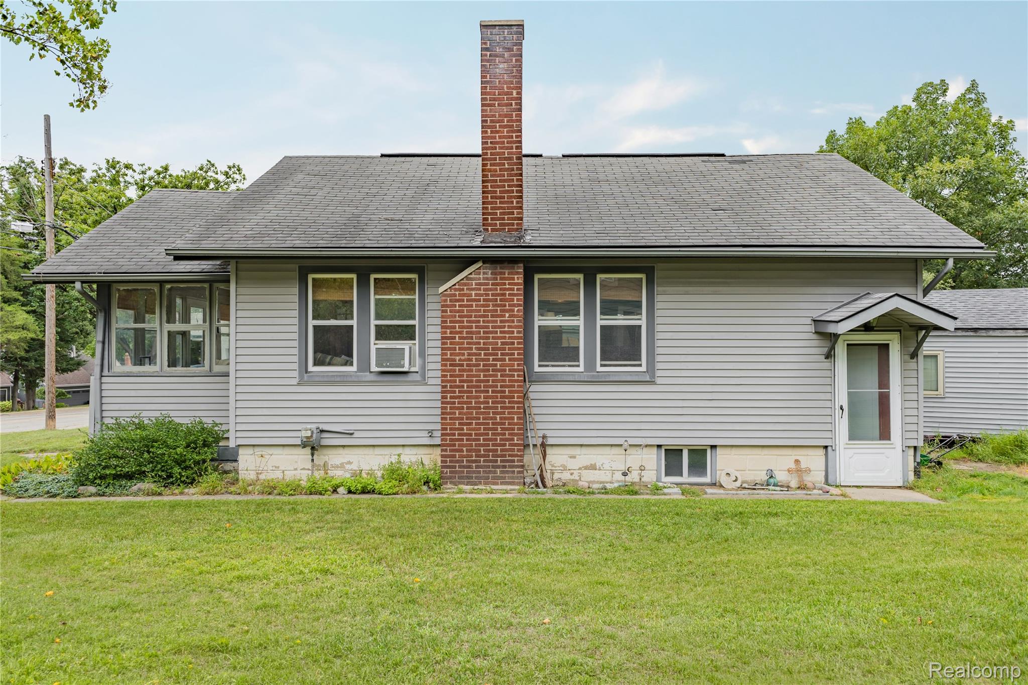 328 Romeo Road Rochester, MI 48307 - Photo 15 of 23 South side of home featuring vinyl Siding exterior with a brick chimney and a pitched roof along with side entry door.