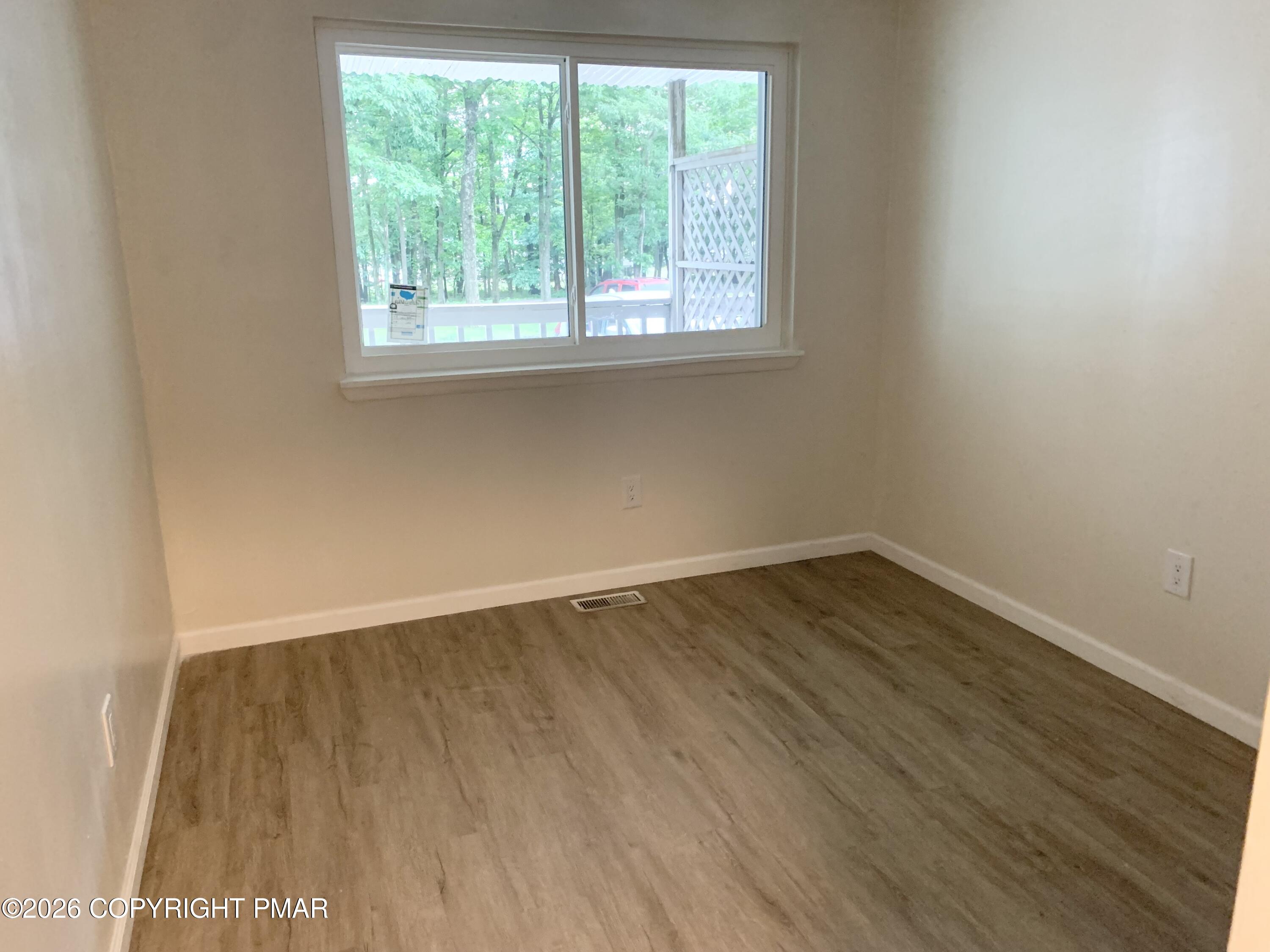 130 View Court, Unit 101 Mount Pocono, PA 18344 - Photo 3 of 8 an empty room with wooden floor and windows