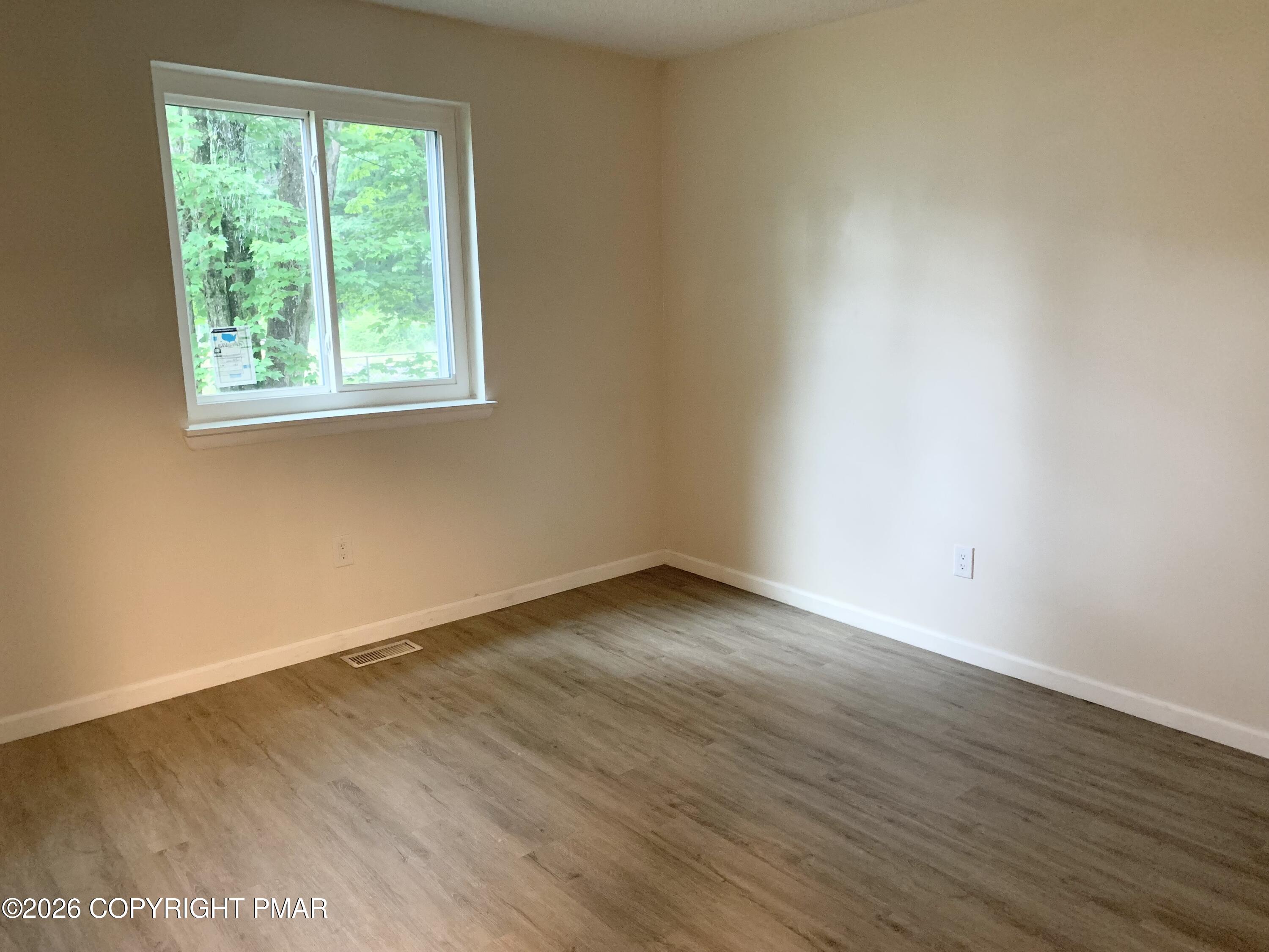 130 View Court, Unit 101 Mount Pocono, PA 18344 - Photo 7 of 8 an empty room with wooden floor and windows
