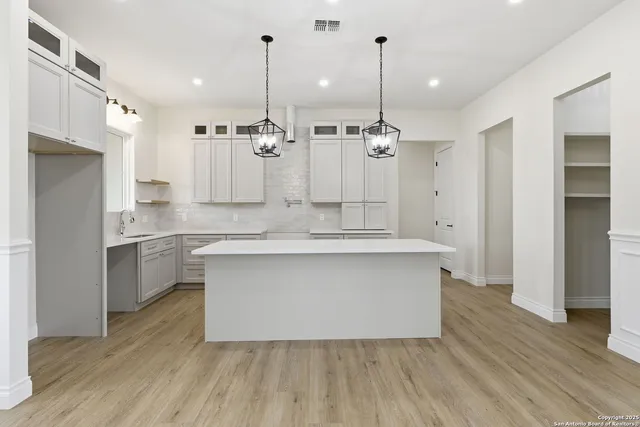 a large kitchen with stainless steel appliances a large counter top a stove a sink and a refrigerator