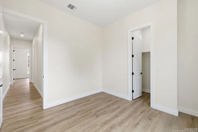 a view of an empty room with a closet and wooden floor