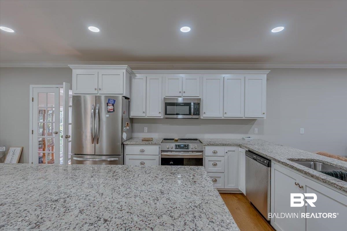 14160 Moffett Road Wilmer, AL 36587 - Photo 8 of 75 Kitchen featuring crown molding, light stone countertops, stainless steel appliances, recessed lighting, and white cabinetry