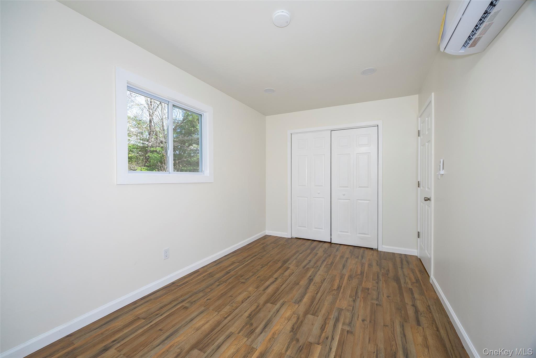 565 Old Hopewell Road Hopewell Junction, NY 12533 - Photo 12 of 23 Unfurnished bedroom featuring a wall unit AC, dark wood finished floors, and a closet