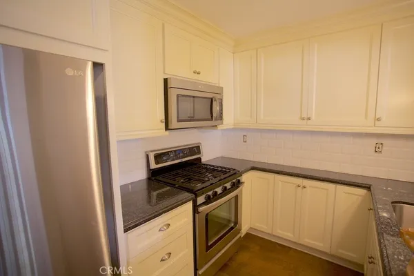 a kitchen with granite countertop white cabinets and stainless steel appliances
