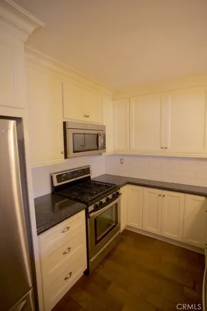 a kitchen with granite countertop white cabinets and black appliances