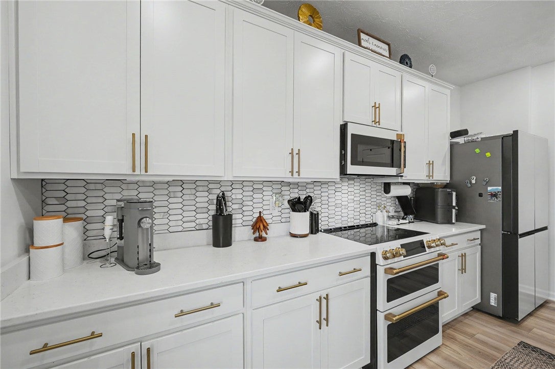 3011 Falls Road Clayton, OH 45315 - Photo 25 of 66 Modern kitchen with white cabinetry and a honeycomb-patterned backsplash.