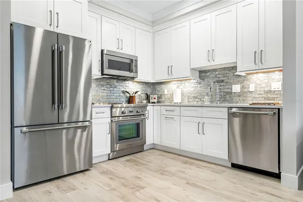 a kitchen with stainless steel appliances granite countertop a refrigerator stove and white cabinets