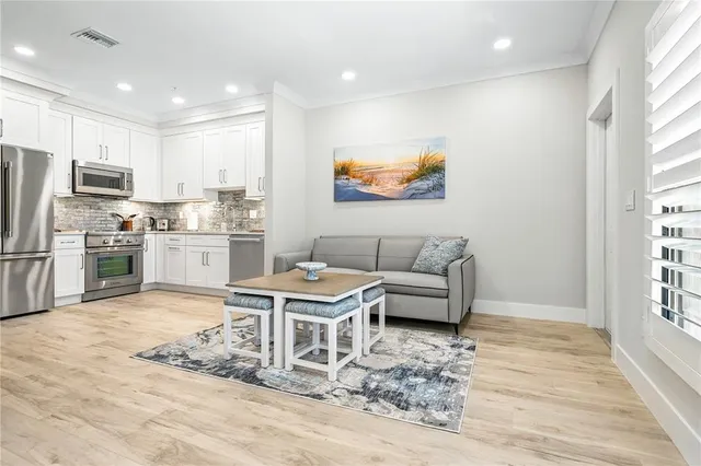 a living room with stainless steel appliances furniture and a kitchen view