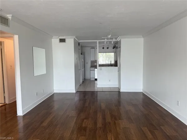 a view of empty room with wooden floor and window