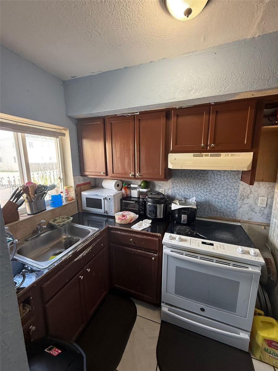 417 Northwest 84th Street, Unit 417 Miami, FL 33150 - Photo 20 of 26 a kitchen with a sink stove and cabinets