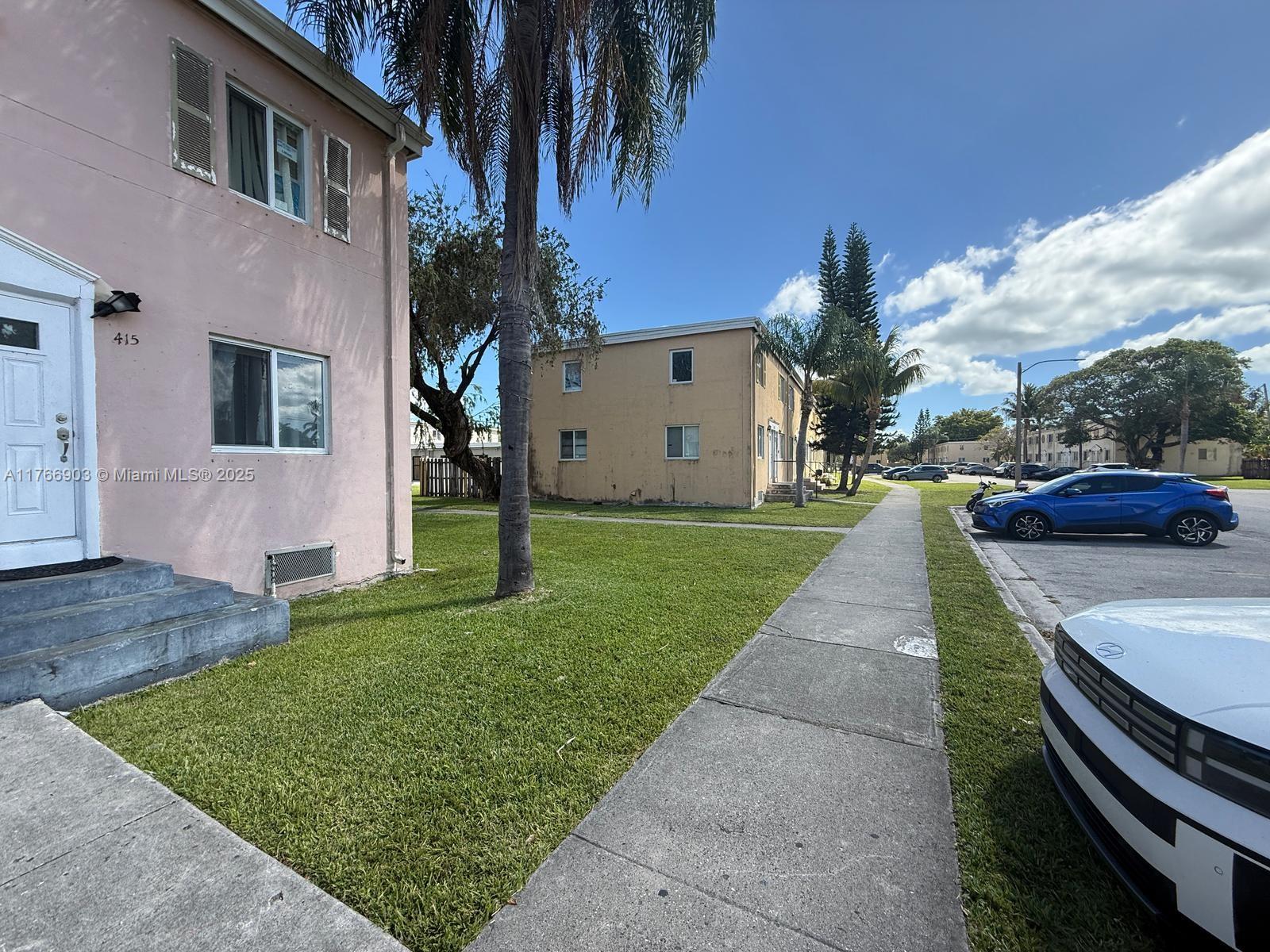 417 Northwest 84th Street, Unit 417 Miami, FL 33150 - Photo 2 of 26 a view of a white house with a yard plants and a table and chairs