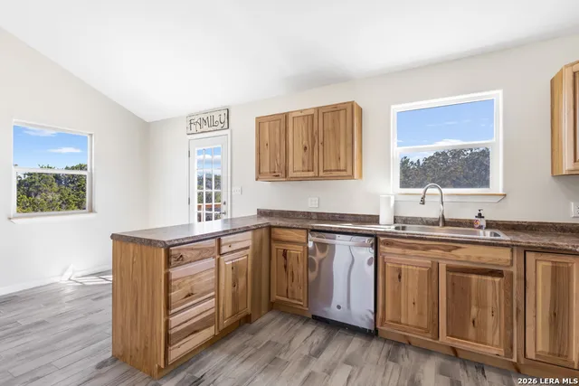 a kitchen with stainless steel appliances granite countertop a sink cabinets and wooden floor