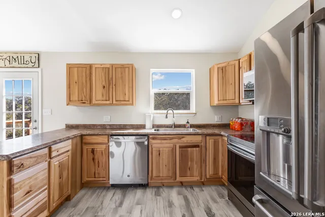 a kitchen with stainless steel appliances granite countertop a sink cabinets and wooden floor