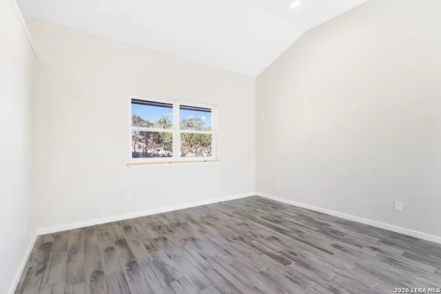 an empty room with wooden floor and window