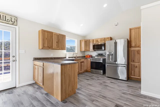 a kitchen with a refrigerator stove and wooden floor