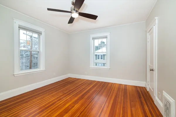 a view of empty room with wooden floor and fan