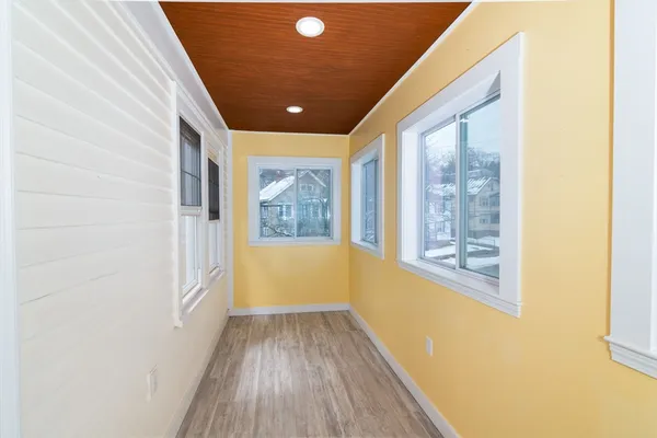 a view of a hallway with wooden floor and a window