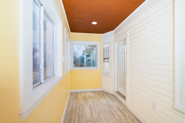 a view of an empty room with wooden floor and a window