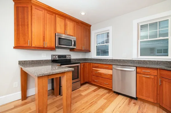 a kitchen with stainless steel appliances granite countertop wooden cabinets a stove top oven with a sink and dishwasher