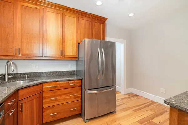 a kitchen with granite countertop wooden cabinets and refrigerator