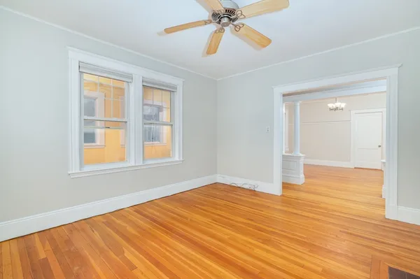 a view of an empty room with wooden floor and a window