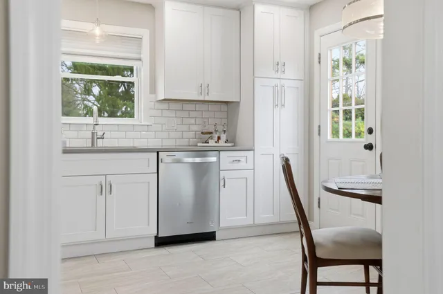 a kitchen with white cabinets and wooden floors