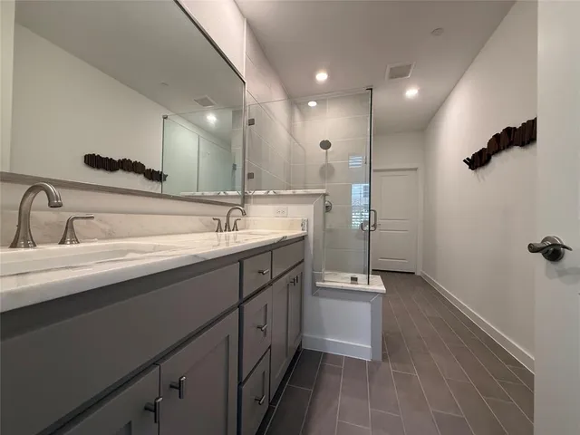 a spacious bathroom with a double vanity sink a mirror and shower