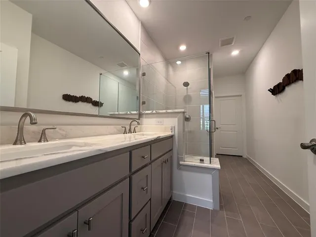 a bathroom with a double vanity sink a mirror and a shower