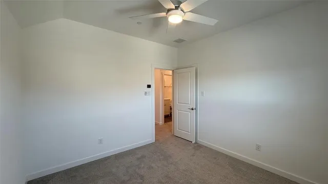 an empty room with a chandelier fan and closet area